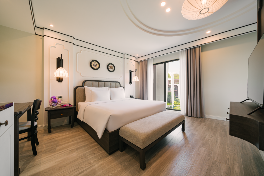 Phòng Junior Suite sang trọng với giường đôi lớn và cửa kính ngập tràn ánh sáng tại Soc Village.