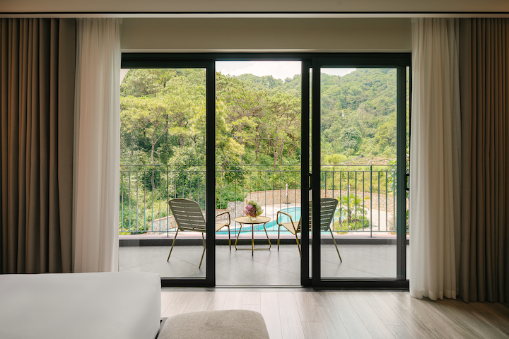 Ban công phòng nghỉ tại Soc Village với bàn ghế thư giãn và tầm nhìn hướng rừng thông, đồi núi xanh mát.