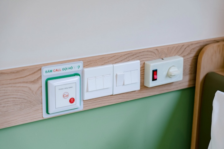 Bảng công tắc điện và nút bấm gọi hỗ trợ khẩn cấp gắn trên ốp gỗ đầu giường
